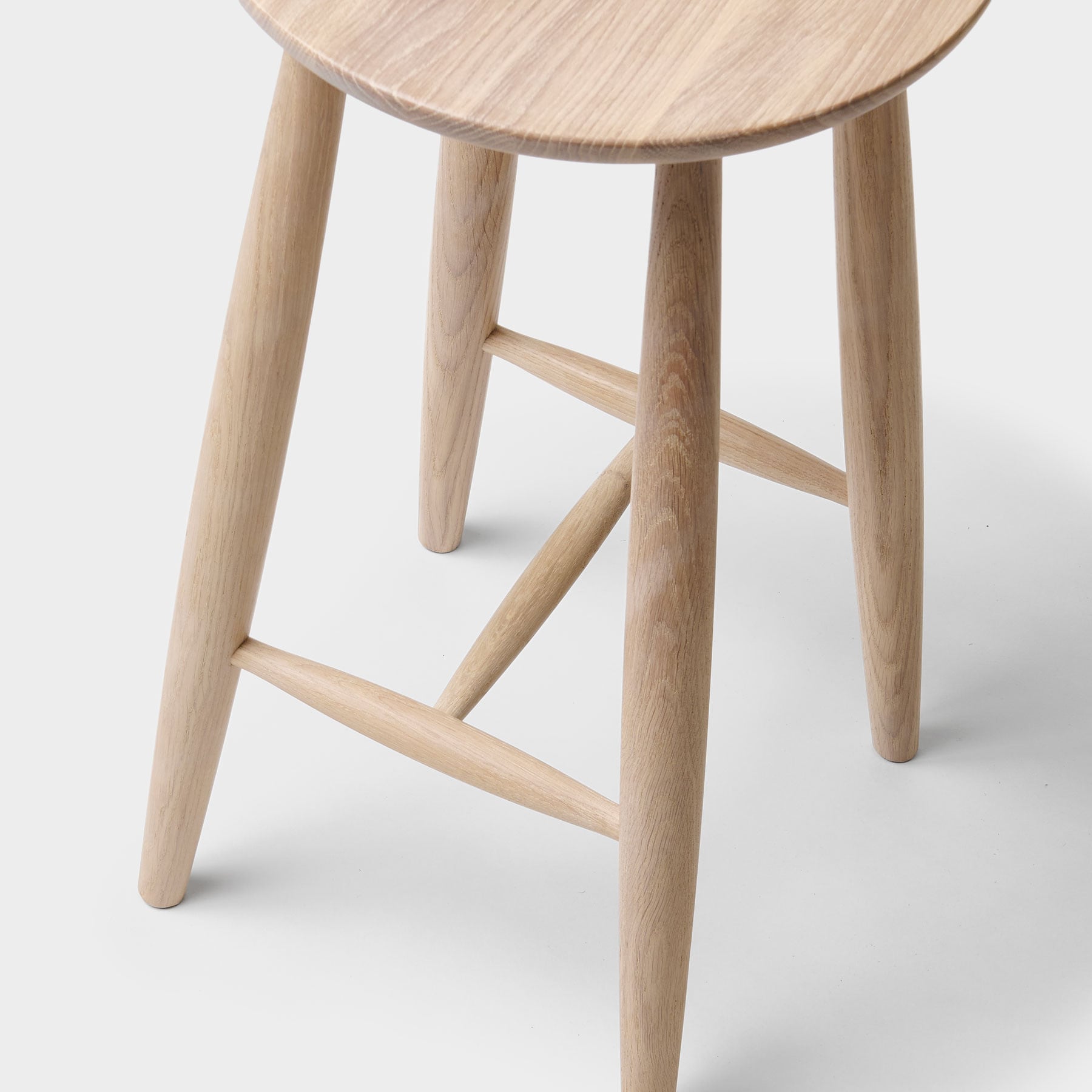 detalj på bena på den runde høye krakken i eik